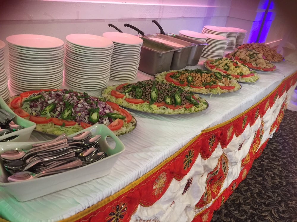 Chafing dishes and plates of food arranged on a catering table.