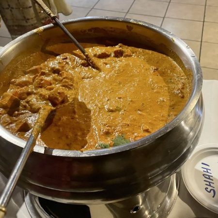 Thick creamy chicken korma curry cooking in a large pot.