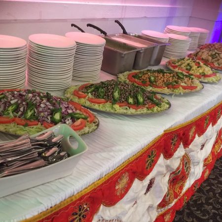 Chafing dishes and plates of food arranged on a catering table.