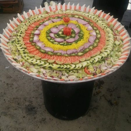 Large round decorative salad platter on a catering display stand.