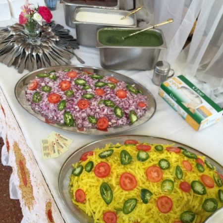 Catering buffet table with colorful rice dishes and salads.
